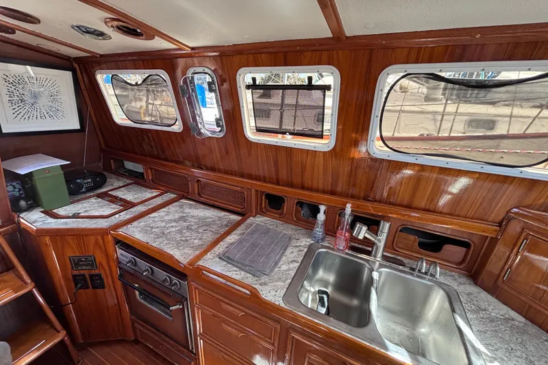 Slide: The Image of Interior of a 1978 Swift 33 boat featuring a wooden kitchen with a sink and stove. - 19