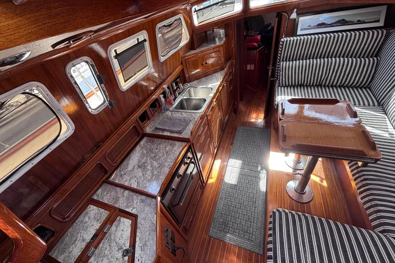 Slide: The Image of Interior of a 1978 Swift 33 boat featuring a wooden kitchen and striped seating. - 18