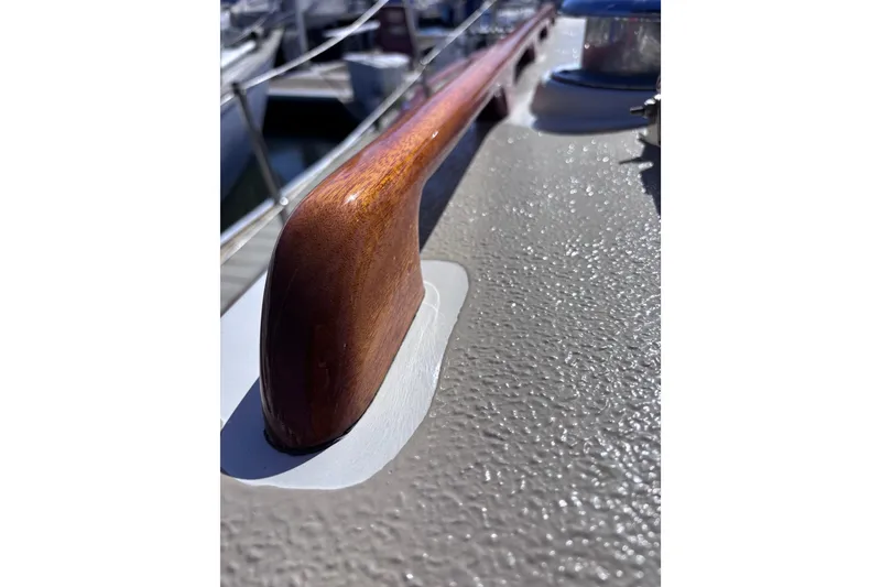 Slide: The Image of Close-up of a 1978 Swift 33 boat's polished wooden handrail and textured deck surface. - 54
