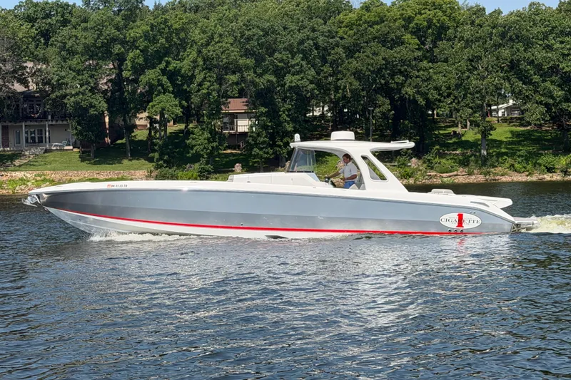Slide: The Image of 2015 Cigarette 41' Nighthawk SD Edition boat cruising on a lake with lush green backdrop. - 2