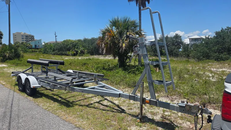 Slide: The Image of A boat trailer is parked on a road next to a grassy area with palm trees. - 19