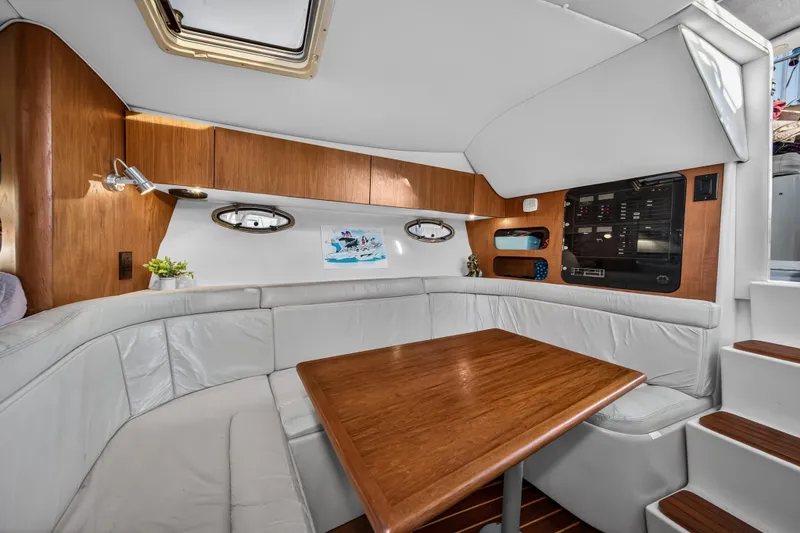 Slide: The Image of Interior of 1995 Tiara Yachts 3100 Open, featuring a cozy seating area and wooden table. - 15