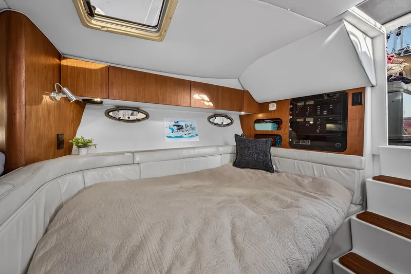 Slide: The Image of Interior cabin of a 1995 Tiara Yachts 3100 Open, featuring a cozy bed and wooden accents. - 14