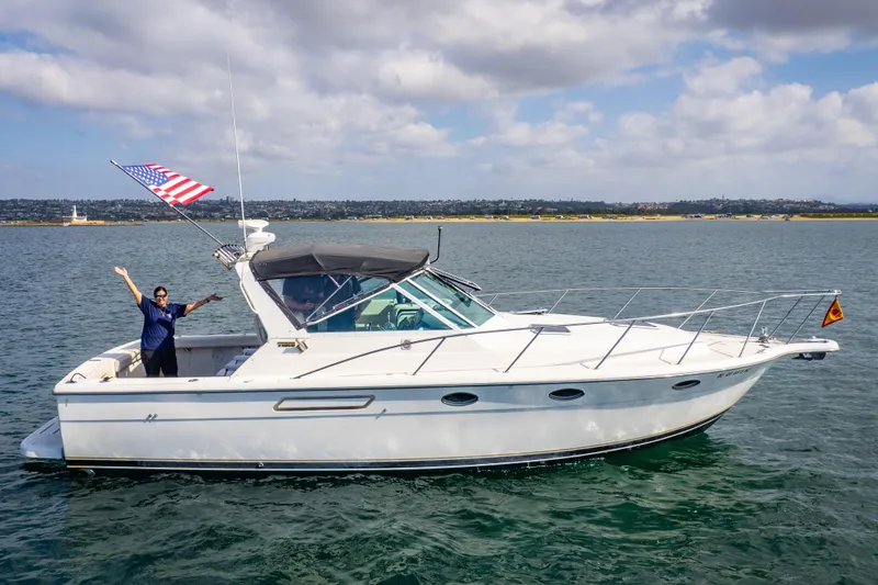 Slide: The Image of 1995 Tiara Yachts 3100 Open cruising on water with person waving, American flag displayed. - 1