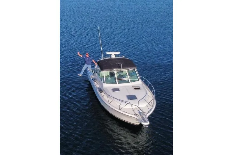 Slide: The Image of 1995 Tiara Yachts 3100 Open on water with person standing on bow. - 3