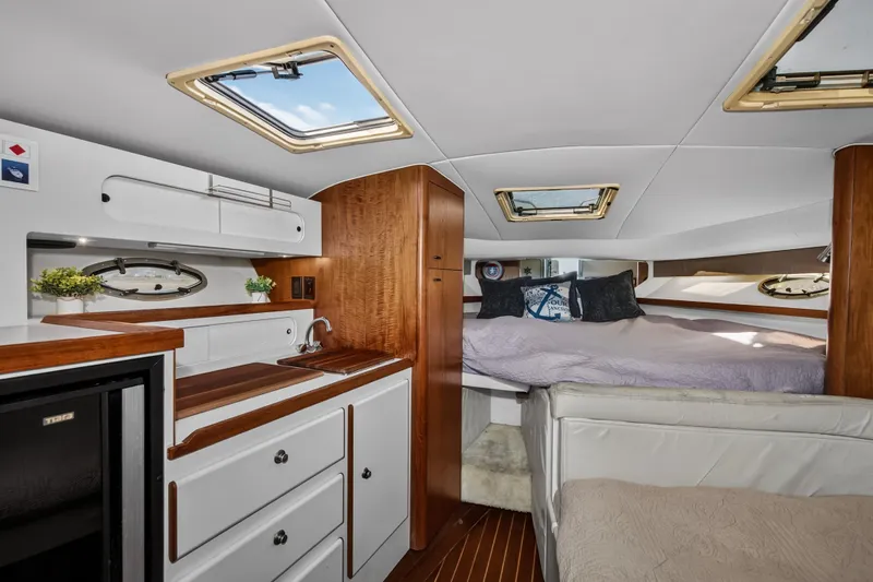 Slide: The Image of Interior of 1995 Tiara Yachts 3100 Open, featuring cozy cabin with bed and kitchenette. - 9