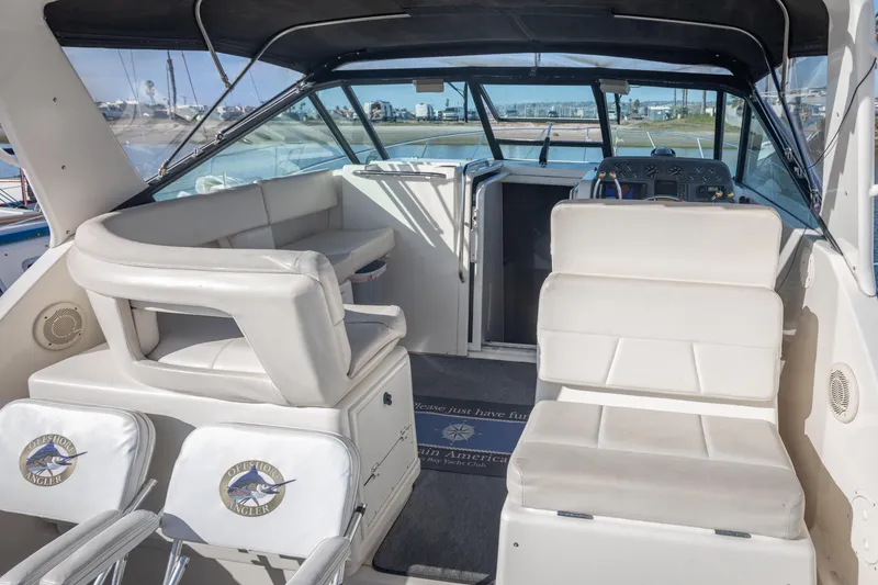 Slide: The Image of 1995 Tiara Yachts 3100 Open interior with white seating and helm, docked at marina. - 19