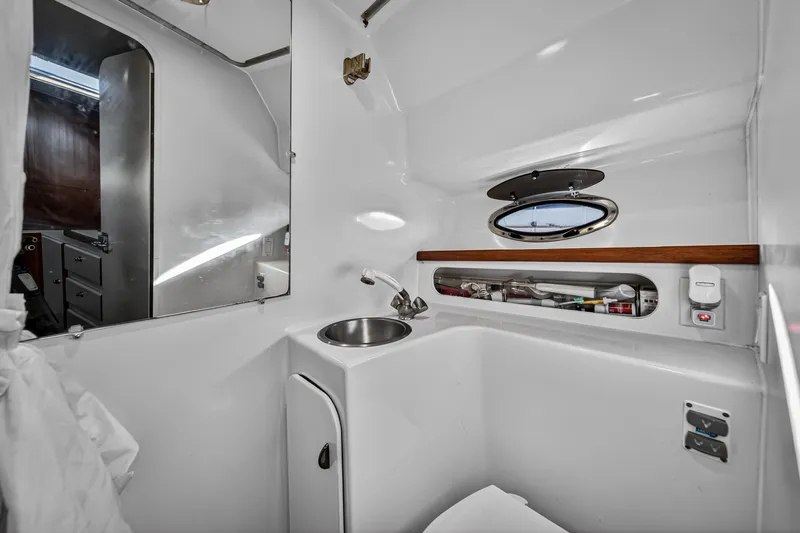 Slide: The Image of Bathroom interior of 1995 Tiara Yachts 3100 Open, featuring sink and porthole window. - 13