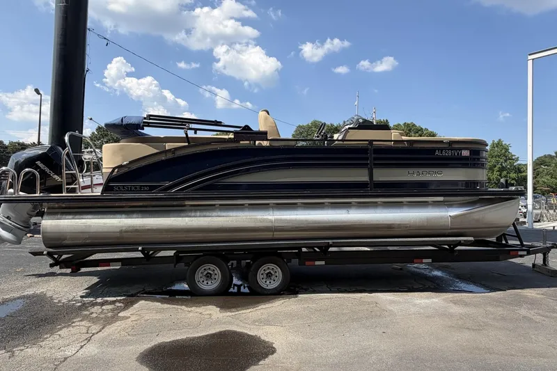 The Image of 2022 Harris Solstice 230 CWDH pontoon boat on trailer under blue sky. - 0