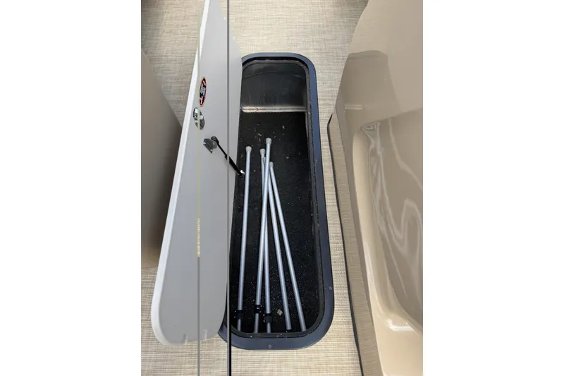 Slide: The Image of Open storage compartment on 2022 Harris Solstice 230 CWDH boat, containing metal poles. - 9