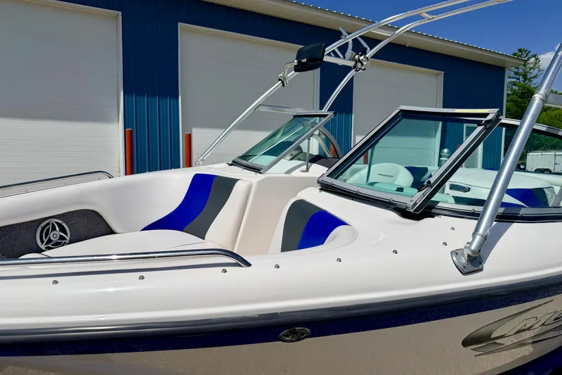 Slide: The Image of 2008 Moomba Outback V boat with blue and white interior, parked near blue building. - 12