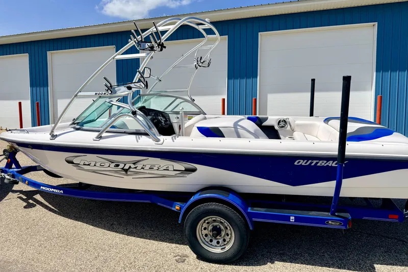 Slide: The Image of 2008 Moomba Outback V boat on trailer, parked near blue building. - 6