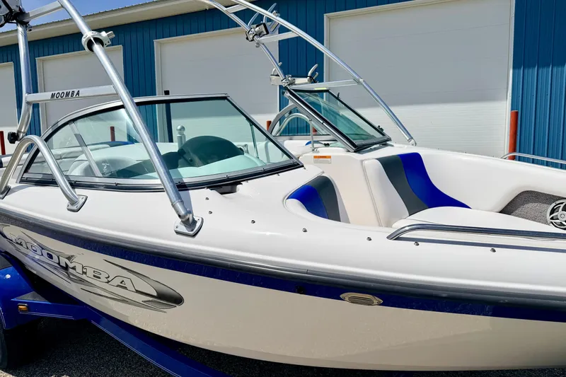 Slide: The Image of 2008 Moomba Outback V boat with blue and white design, parked near a blue building. - 8