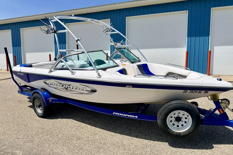 Slide: The Image of 2008 Moomba Outback V boat on trailer, parked near blue warehouse. - 3