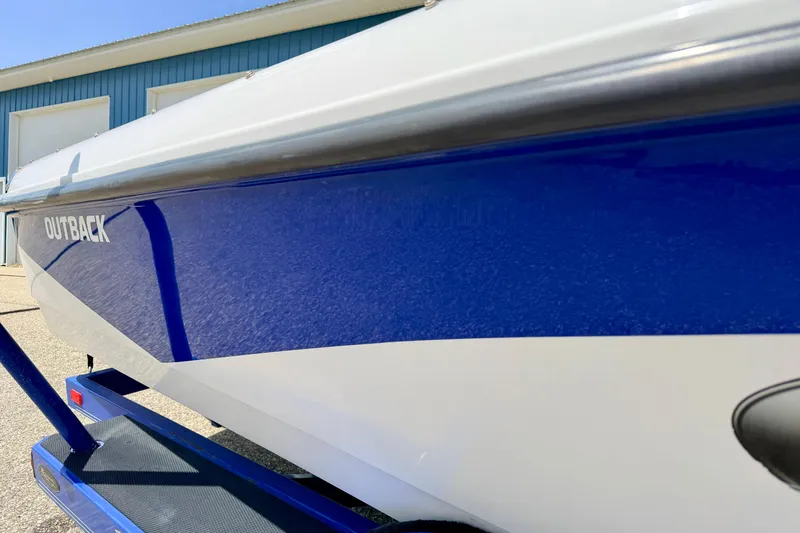 Slide: The Image of 2008 Moomba Outback V boat with blue and white exterior, parked near a blue building. - 11