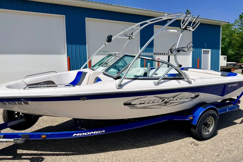 Slide: The Image of 2008 Moomba Outback V boat on trailer, parked near blue building. - 4