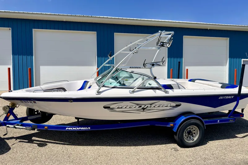 Slide: The Image of 2008 Moomba Outback V boat on trailer, parked outside blue building. - 2