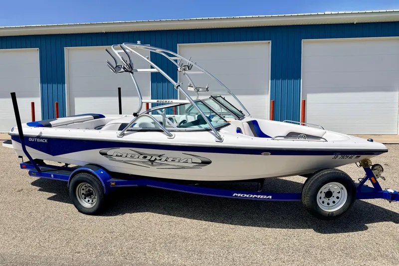 The Image of 2008 Moomba Outback V boat on trailer, parked outside blue building. - 1