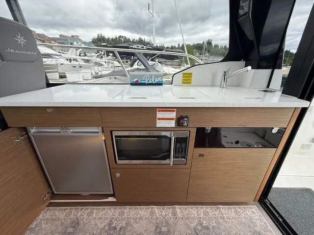 Slide: The Image of Interior of the Jeanneau NC 1095 featuring a modern kitchen and harbor view. - 13