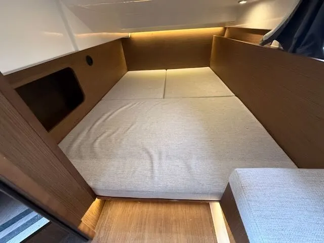 Slide: The Image of Interior of a 2021 Jeanneau NC 1095 with a cozy sleeping area and wood paneling. - 25