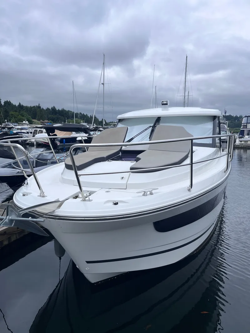 Slide: The Image of A 2021 Jeanneau NC 1095 docked in a marina. It features a modern design and spacious foredeck area. - 40