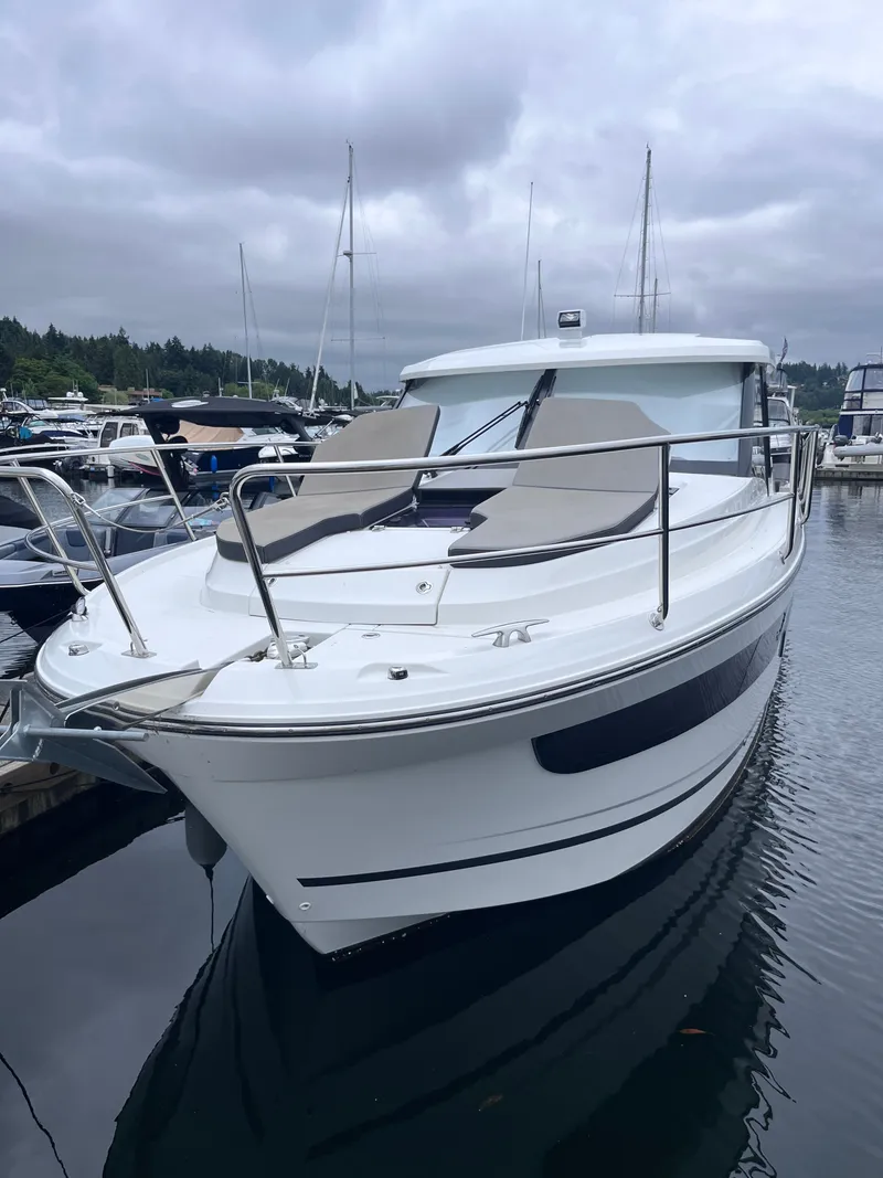 Slide: The Image of A 2021 Jeanneau NC 1095 boat docked in a marina. It features a sleek design and comfortable sun pads. - 38