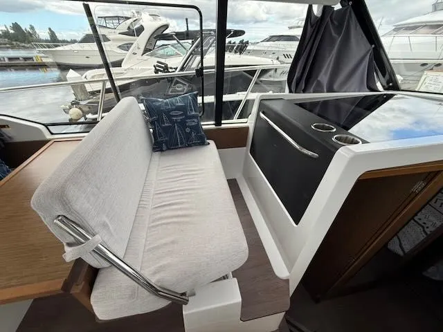 Slide: The Image of Interior of a Jeanneau NC 1095 with a bench and table, surrounded by other boats in the marina. - 9