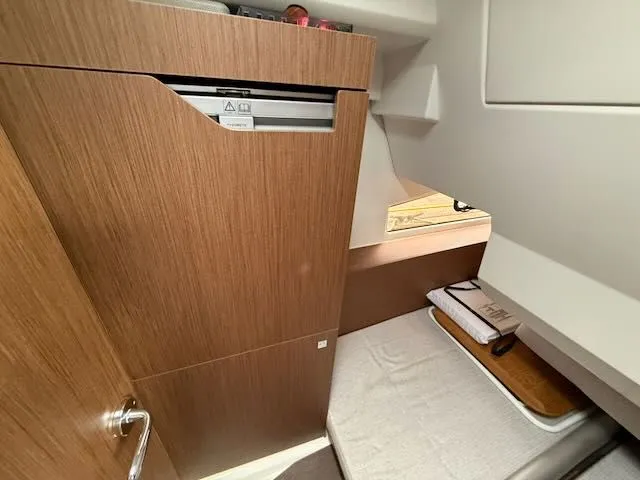Slide: The Image of Interior of the Jeanneau NC 1095 featuring wood cabinetry and a single bed. - 31