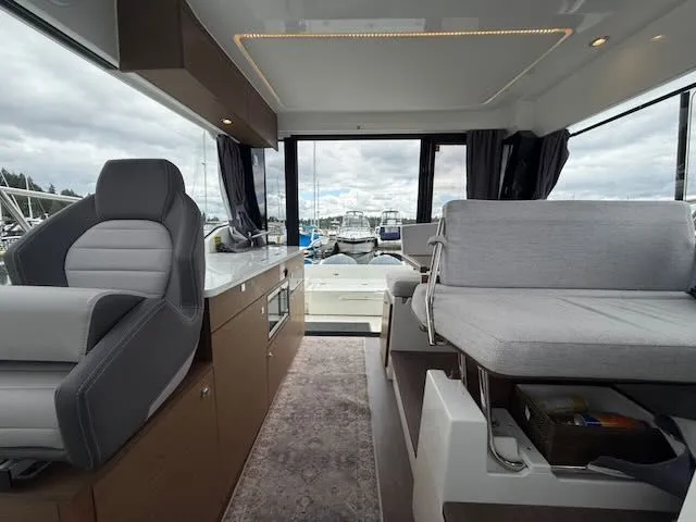 Slide: The Image of Interior of a 2021 Jeanneau NC 1095 with gray seating and large windows. - 22