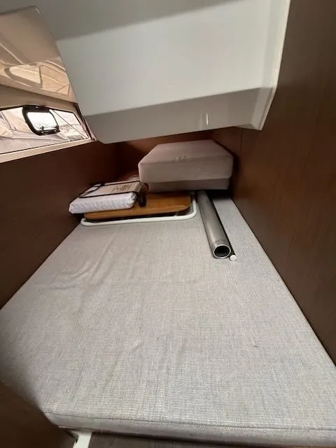 Slide: The Image of Interior of a 2021 Jeanneau NC 1095 with cushioned bed and wood paneling. - 32