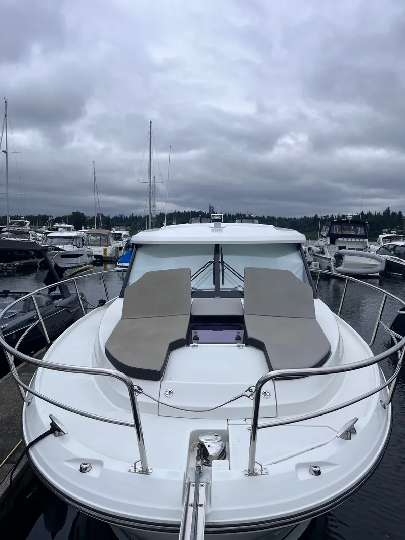 Slide: The Image of A 2021 Jeanneau NC 1095 docked in a marina. It features a spacious foredeck with seating. - 37