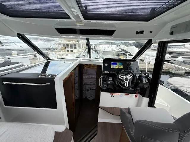 Slide: The Image of Interior view of a modern boat helm with gray seating and a large steering wheel. Windows overlook the marina. - 21