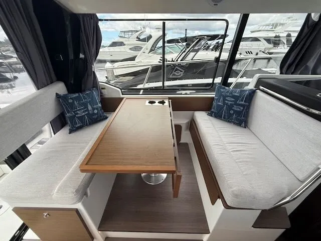 Slide: The Image of Interior of the Jeanneau NC 1095 featuring a sleek wooden table and comfortable bench seating. - 5