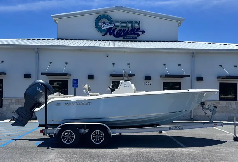 The Image of A Key West 203 FS boat on a trailer in front of a building with "Ocean Marine" signage. - 1