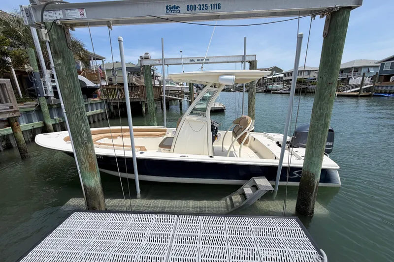 Slide: The Image of 2012 Scout 251 XS boat docked in a marina, surrounded by waterfront homes. - 9