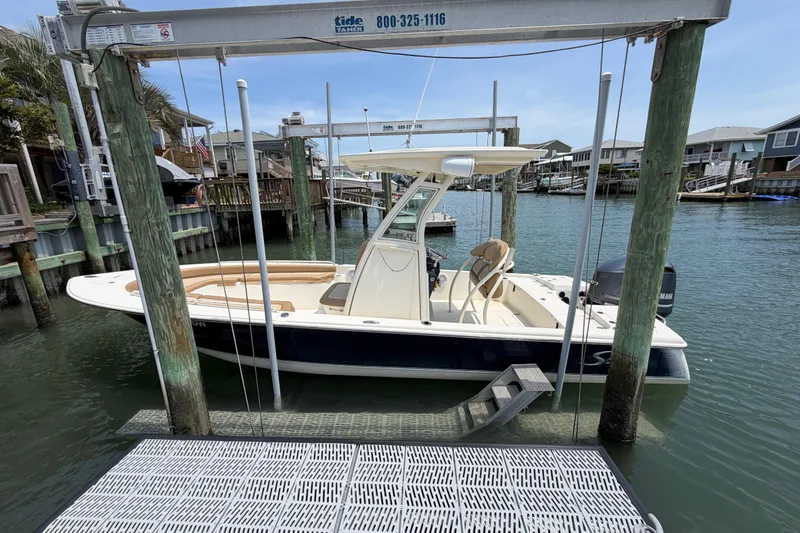 Slide: The Image of 2012 Scout 251 XS boat docked in a marina, surrounded by waterfront homes. - 1