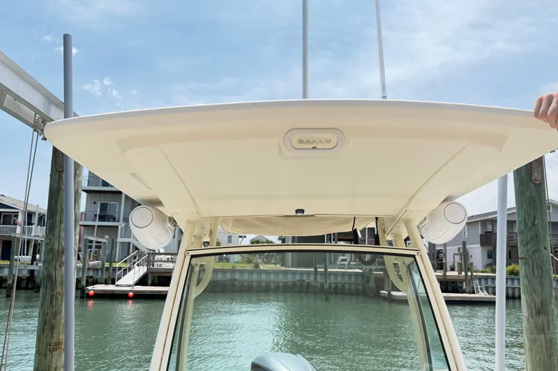 Slide: The Image of 2012 Scout 251 XS boat with T-top and speakers, docked by waterfront homes. - 5