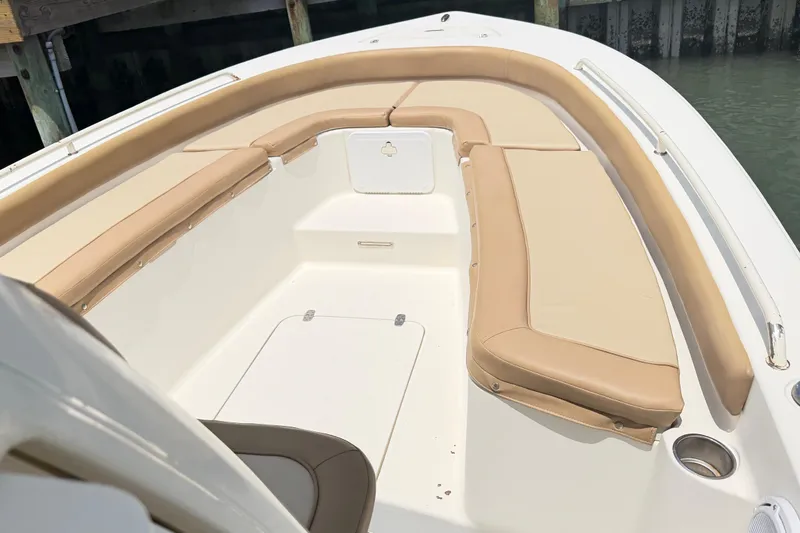 Slide: The Image of 2012 Scout 251 XS boat interior with beige cushioned seating and white deck. - 2