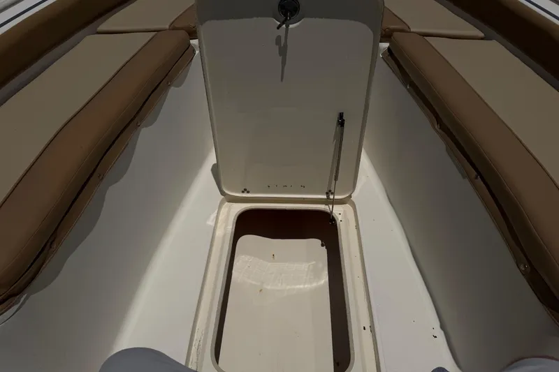 Slide: The Image of 2012 Scout 251 XS boat interior with open storage compartment and cushioned seating. - 19