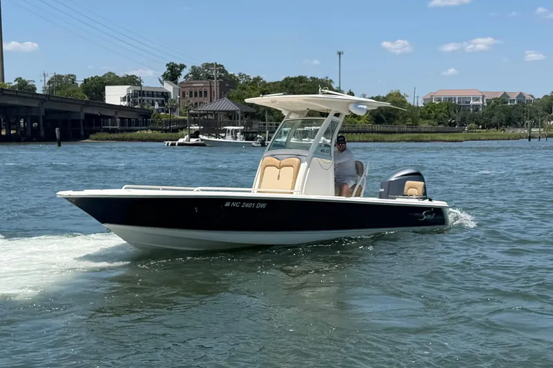 Slide: The Image of 2012 Scout 251 XS boat cruising on a sunny day near a bridge and waterfront homes. - 5