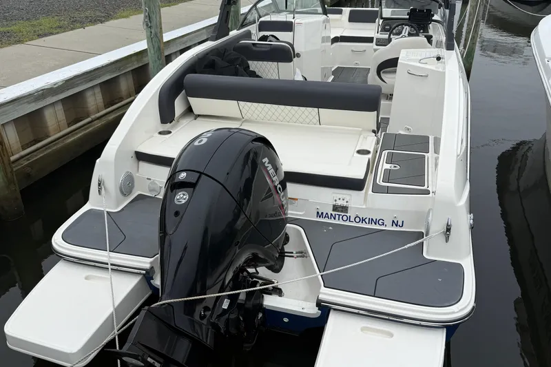 Slide: The Image of 2021 Bayliner DX 2200 boat docked, featuring a Mercury outboard motor. - 5