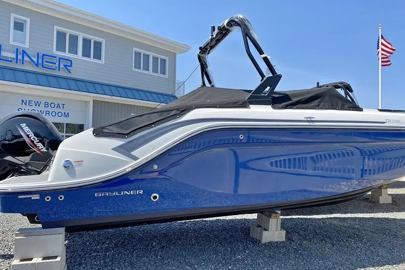 Slide: The Image of 2021 Bayliner DX 2200 boat displayed outside showroom with American flag. - 2