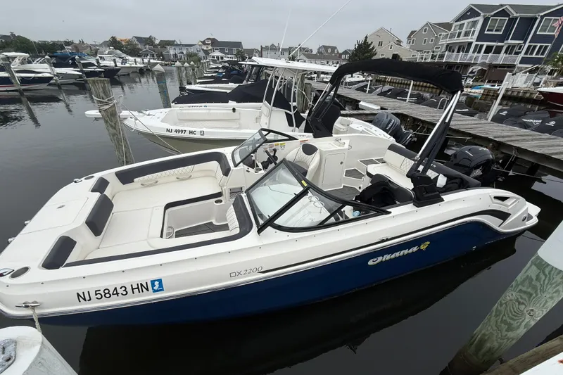 Slide: The Image of 2021 Bayliner DX 2200 boat docked in a marina, surrounded by other vessels. - 3