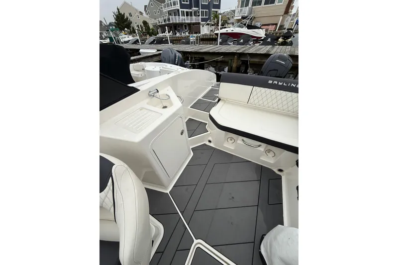 Slide: The Image of 2021 Bayliner DX 2200 boat interior with seating and storage, docked at marina. - 8