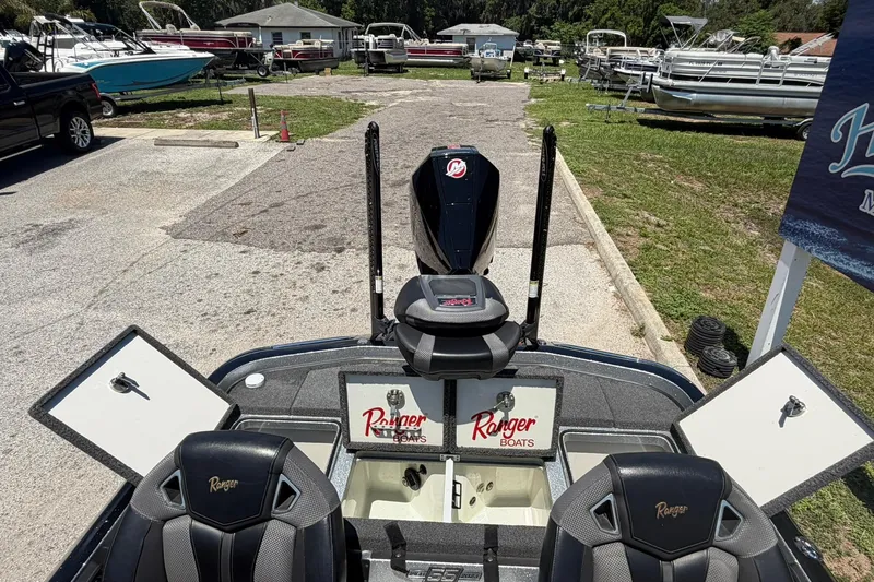 Slide: The Image of 2023 Ranger Z521R boat interior with open storage compartments and seating at a marina. - 13