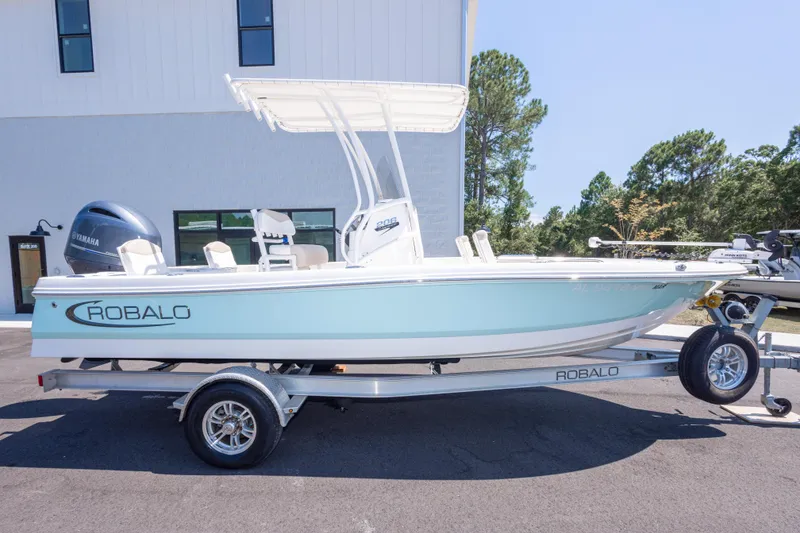 Slide: The Image of 2023 Robalo 206 Cayman boat on trailer, parked outdoors, featuring Yamaha engine. - 2