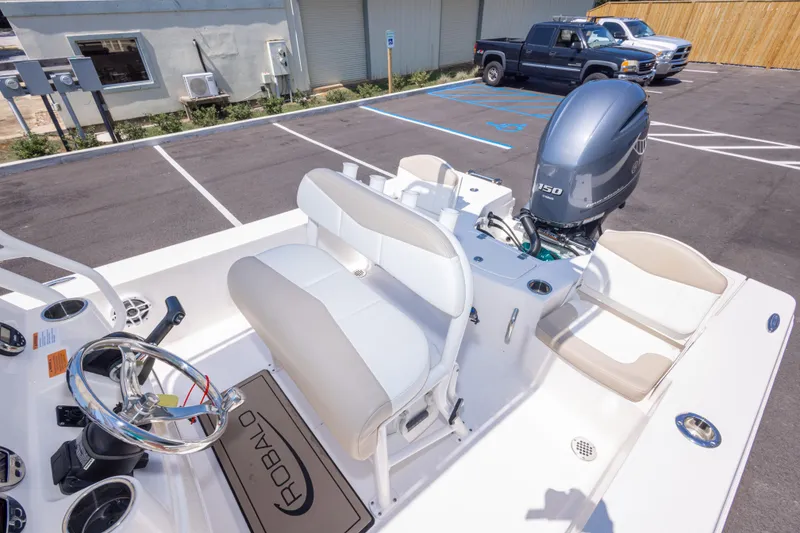 Slide: The Image of 2023 Robalo 206 Cayman boat interior with steering wheel and seating in a parking lot. - 28
