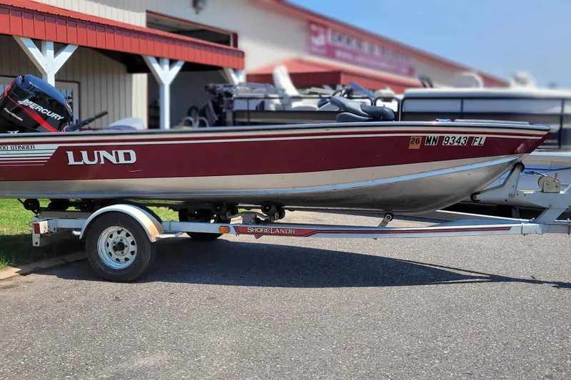 Slide: The Image of 1989 Lund 1600 Stinger boat on trailer, parked outside a building. - 5