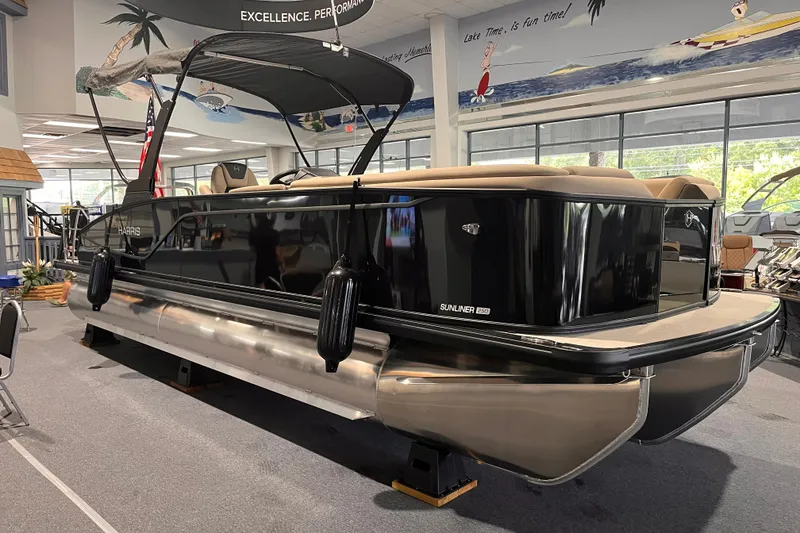 The Image of 2026 Harris Sunliner 250 pontoon boat displayed indoors, featuring sleek black design and comfortable seating. - 0