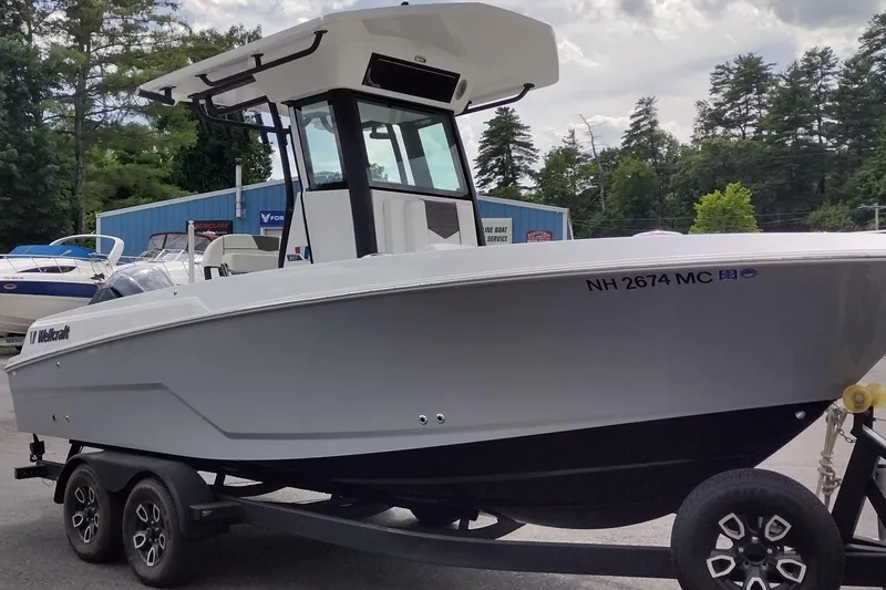 Slide: The Image of 2024 Wellcraft 223 Fisherman boat on trailer, parked outdoors near trees and buildings. - 3